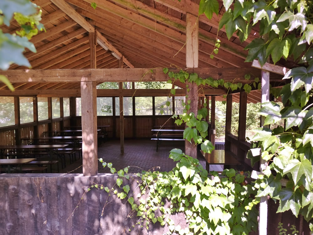 Aufenthaltsraum und Grillplatz im Ferienzentrum Ein überdachter Aufenthaltsraum aus Holz neben einem Grillplatz im Ferienzentrum Albert Schweitzer in Vöhl.