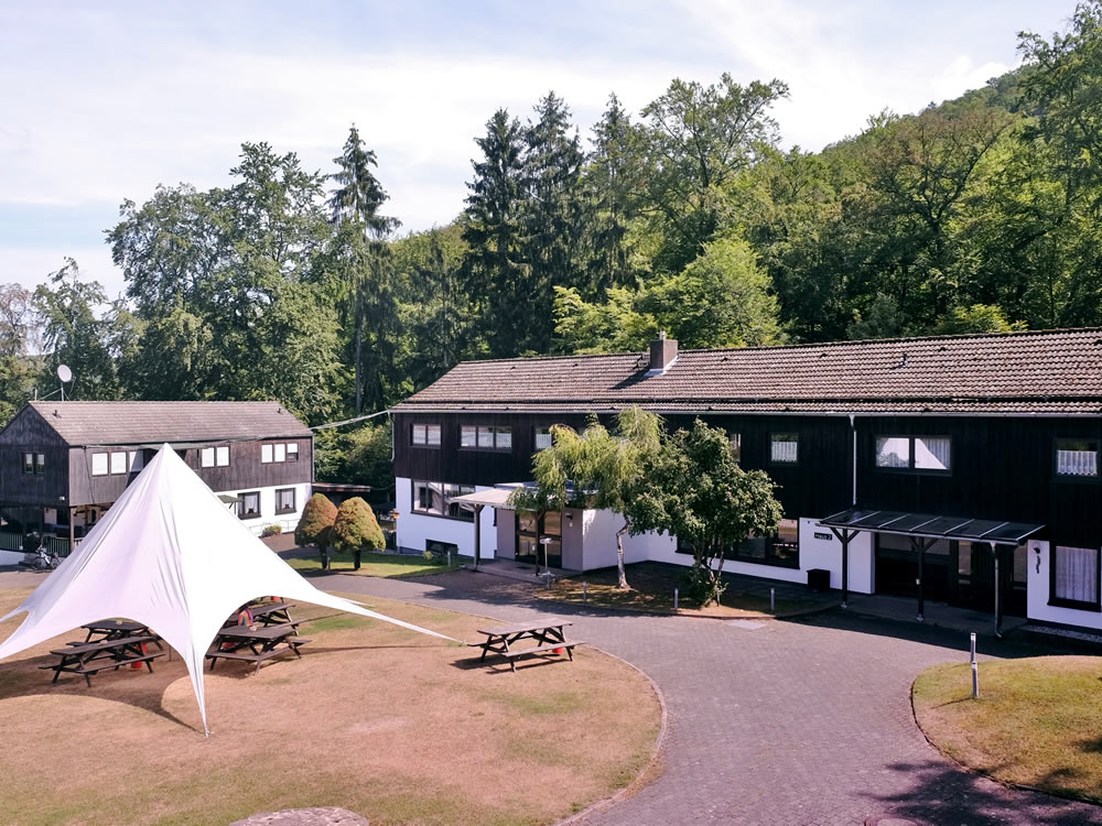 Aussenbereich Ferienzentrum Albert Schweitzer Vöhl Der Außenbereich des Ferienzentrums Albert Schweitzer in Vöhl mit Gebäuden, Tischen und einem Sonnensegel.