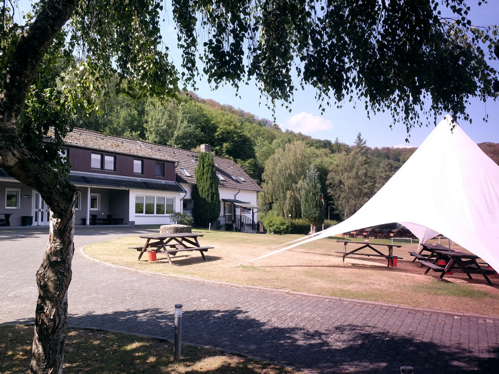Aussenbereich Ferienzentrum Albert Schweitzer Vöhl Der Außenbereich des Ferienzentrums Albert Schweitzer in Vöhl mit Gebäuden, Tischen und einem Sonnensegel.