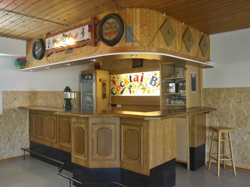 Bar im Ferienzentrum Albert Schweitzer in Vöhl Eine hölzerne Bar mit Beleuchtung und Dekoration im Ferienzentrum Albert Schweitzer in Vöhl. Ein Barhocker steht bereit.